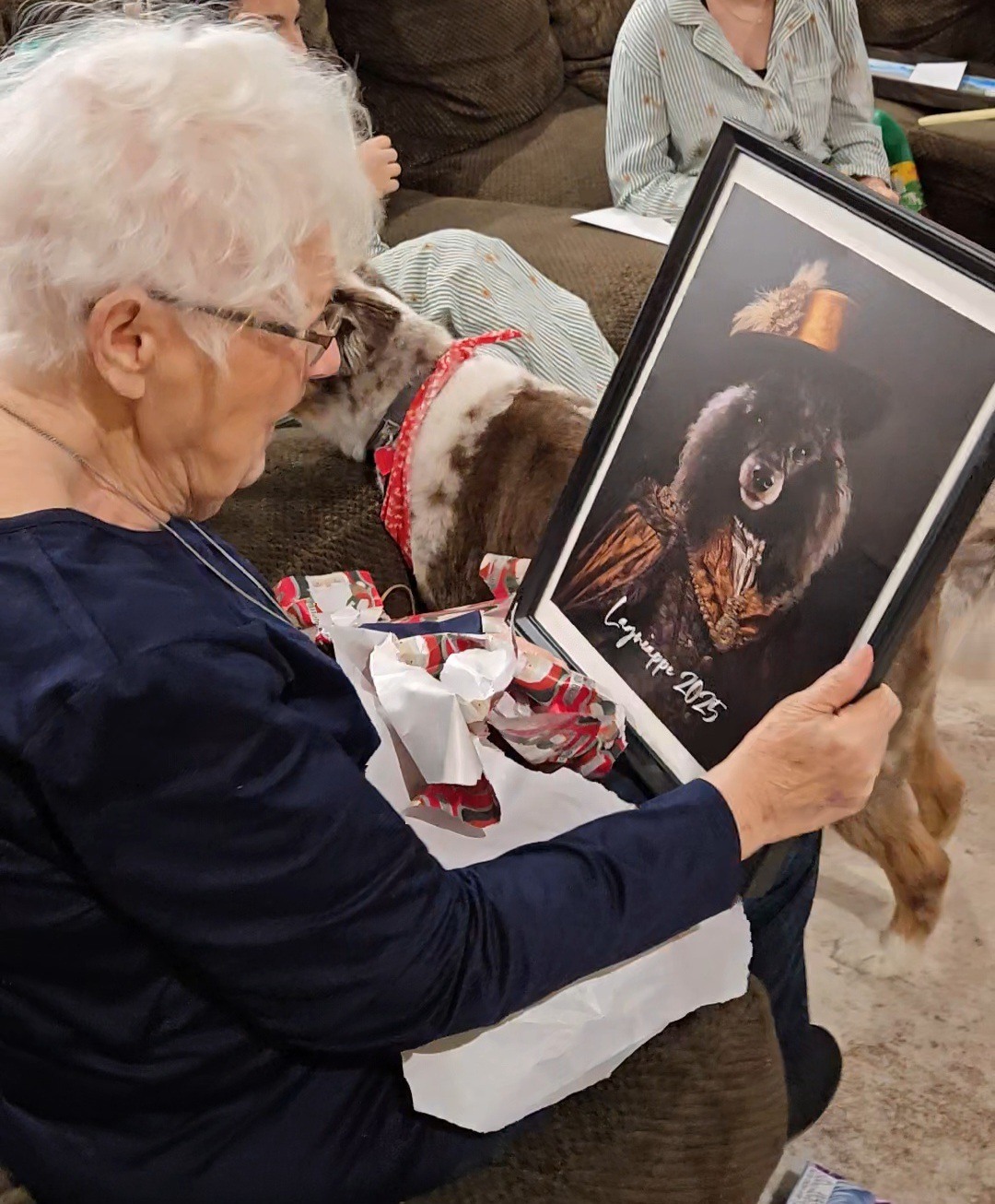 Pet owner holding a framed custom portrait beside her dog